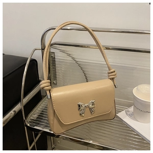 Détail du sac baguette abricot avec nœud en métal argenté et bandoulière nouée