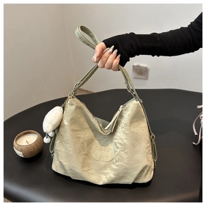 Detailed view of light green pleated tote bag with plush charm and brand patch