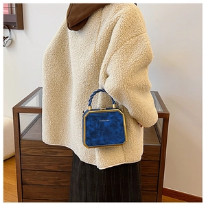 Blauwe fluwelen boxbag met gouden metalen frame en gedraaid handvat gedragen door model