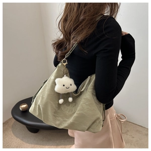Light green nylon tote bag with plush cloud charm shown on model in a modern setting