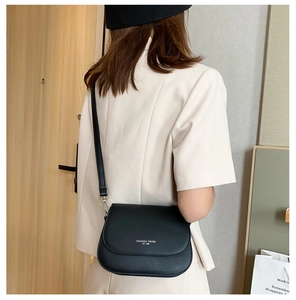 Detail of minimalist black matte saddle bag with white lettering on adjustable strap
