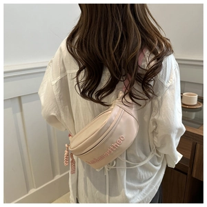 Detailed back view of a beige crossbody bag with pink embroidery and braided zipper pull