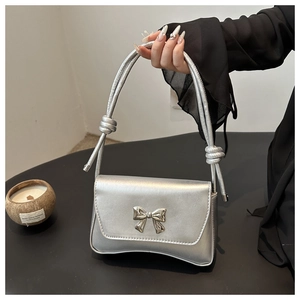 Détail d'un sac à main argenté avec noeud métallique et bandoulière nouée au style moderne
