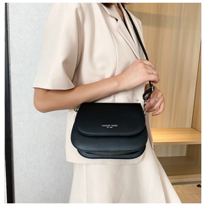 Detailed view of black matte leather saddle bag with fashion trend text worn by model