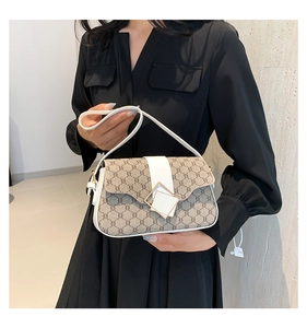 Détail du sac à bandoulière vintage avec boucle dorée et rayures blanches chic