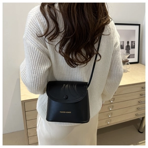 Detail of a chic black leather bucket bag with a fold-over flap and gold logo lettering