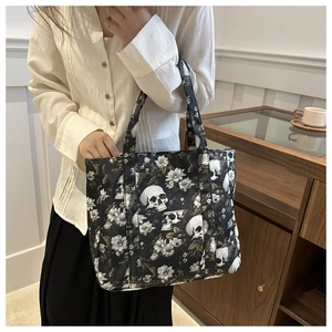 Detail of gothic skull and floral print on lightweight black tote bag held by model