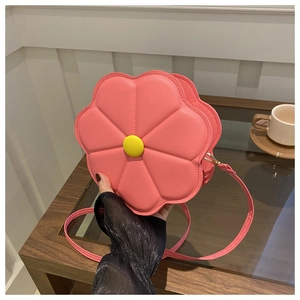 Detail of pink flower shaped crossbody bag featuring embossed petals and yellow button center