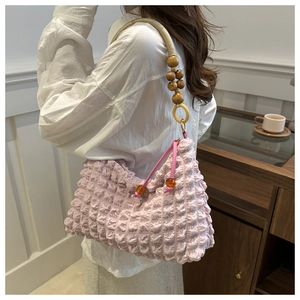 Détails de la texture plissée rose du sac avec anse en corde et perles en bois