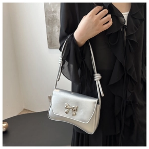 Détail du sac à main argenté métallisé avec boucle nœud élégante et bandoulière fine