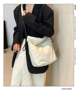 Detail of cream nylon crossbody bag featuring braided rope strap and metal buckle pocket