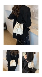 Detail of white drawstring bucket bag featuring 3D heart embossed patterns and thin strap