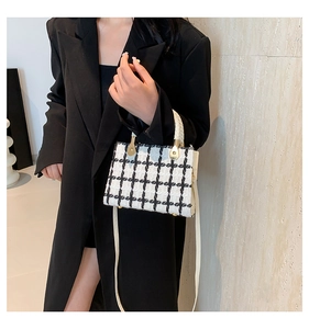 Detail of a chic black and white houndstooth wool handbag with a woven handle and gold accents