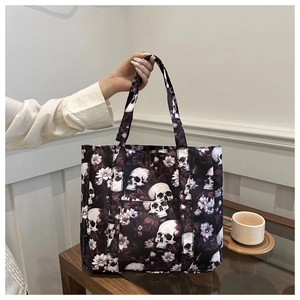 Detail of gothic tote bag with skull and floral print featuring front pocket and handles