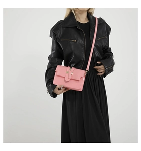 Close-up of bright pink textured square crossbody bag with gold buckle on model