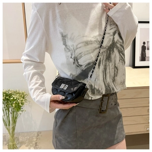 Détail d'un mini sac matelassé noir avec bandoulière chaîne et fermoir rotatif argenté