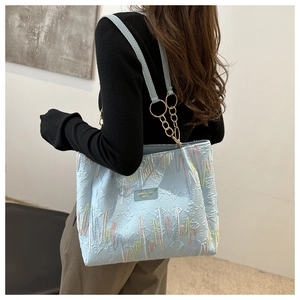 Détail du cabas bleu clair avec broderies ondulées colorées et bandoulière en cuir