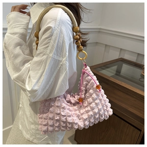 Détail du sac plissé rose avec poignée en perles de bois et cordelette tressée
