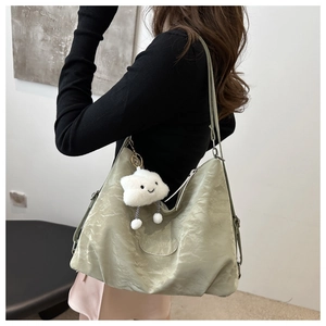 Detail of light green pleated tote bag featuring a white fluffy cloud charm pendant