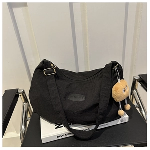 Close-up of black nylon tote bag featuring a fashion logo patch and cute plush charm