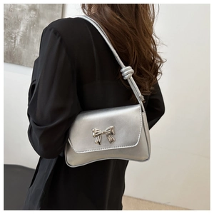 Détail du sac en cuir argenté avec fermoir nœud métallique et bandoulière à nœud décoratif