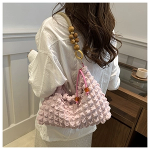 Détail du sac rose texture bulle avec bandoulière en perles de bois et cordon serrage