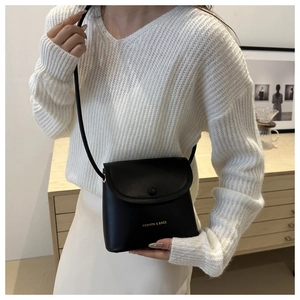 Minimalist black square crossbody bag with gold fashion lettering on white knit outfit