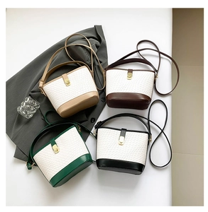 Close-up of four woven bucket bags in beige, brown, green, and black with golden buckles