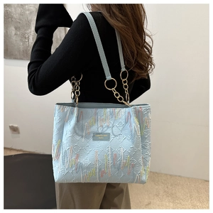 Sac fourre-tout bleu clair avec broderies colorées et chaîne dorée sur mannequin