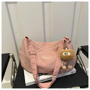 Detail of pink hobo bag with nylon texture, fashion patch and brown plush doll charm