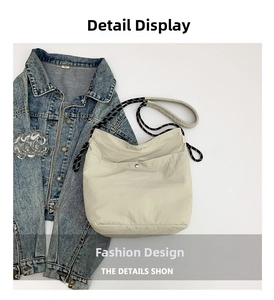 Detail view of cream nylon tote bag featuring nautical rope strap and metal buckle accent