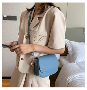 Detail of light blue saddle bag featuring adjustable strap and fashion trend logo