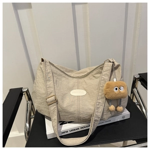Detail of a pleated tote bag with FASHION label and cute brown plush charm on a chair
