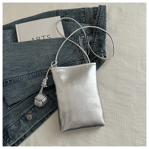 Gros plan détaillé du sac à bandoulière argenté métallisé avec nœud et texture froissée