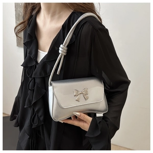 Détail du nœud argenté sur le sac à bandoulière métallisé avec bandoulière à nœuds
