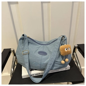 Detail of light blue pleated nylon hobo bag with adjustable strap and cute plush charm