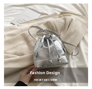 Macro shot of silver pleated bucket bag featuring metallic heart shaped applique details