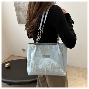 Détail d'un cabas bleu clair avec broderie colorée et bandoulière en chaîne dorée