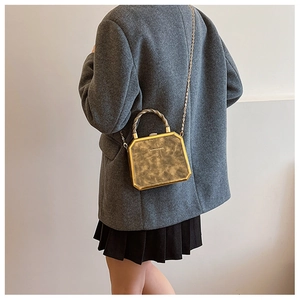 Detail van vintage boxtas met donkere marmertextuur en gouden handvat op het model