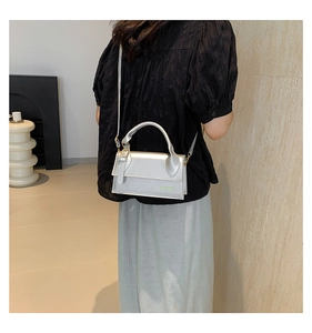 Detail view of silver metallic crossbody bag featuring subtle logo and magnetic closure