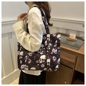 Detailed view of skull and floral print tote bag worn on shoulder for casual styling