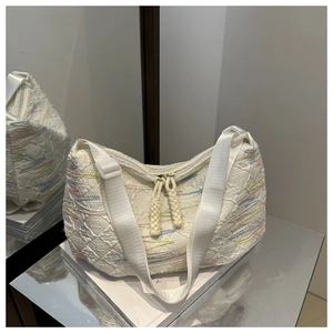 Detail of white embossed fabric shoulder bag with colorful embroidery and woven rope zipper pull