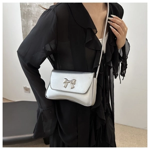 Mannequin portant un sac bandoulière argenté rectangulaire avec un nœud métallique chic