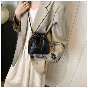 Close-up of black drawstring bucket bag with heart appliques on a stylish outfit