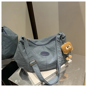 Detail of blue nylon shoulder bag with fashion label and plush toast charm accessory