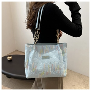 Détail du cabas bleu clair avec texture matelassée et broderies ondulées colorées