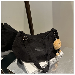 Close-up of black pleated tote bag with fashion label and yellow plush pendant