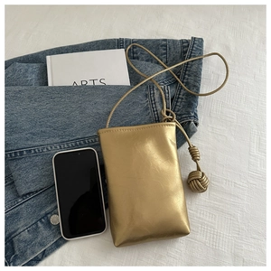 Détail du sac à bandoulière doré métallisé avec texture froissée et nœud tressé