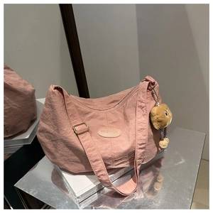 Detail of pink nylon tote bag with fashion label and cute brown plush charm accessory