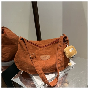 Detailed shot of caramel nylon tote bag with a fun plush bread charm and fashion patch